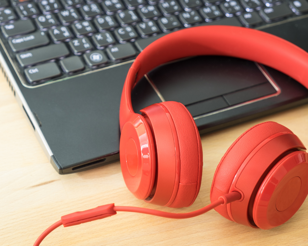 laptop on a desk with orange headphones