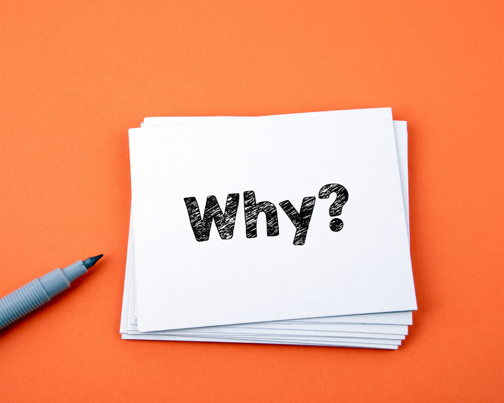 White card on an orange background with the word why written.
