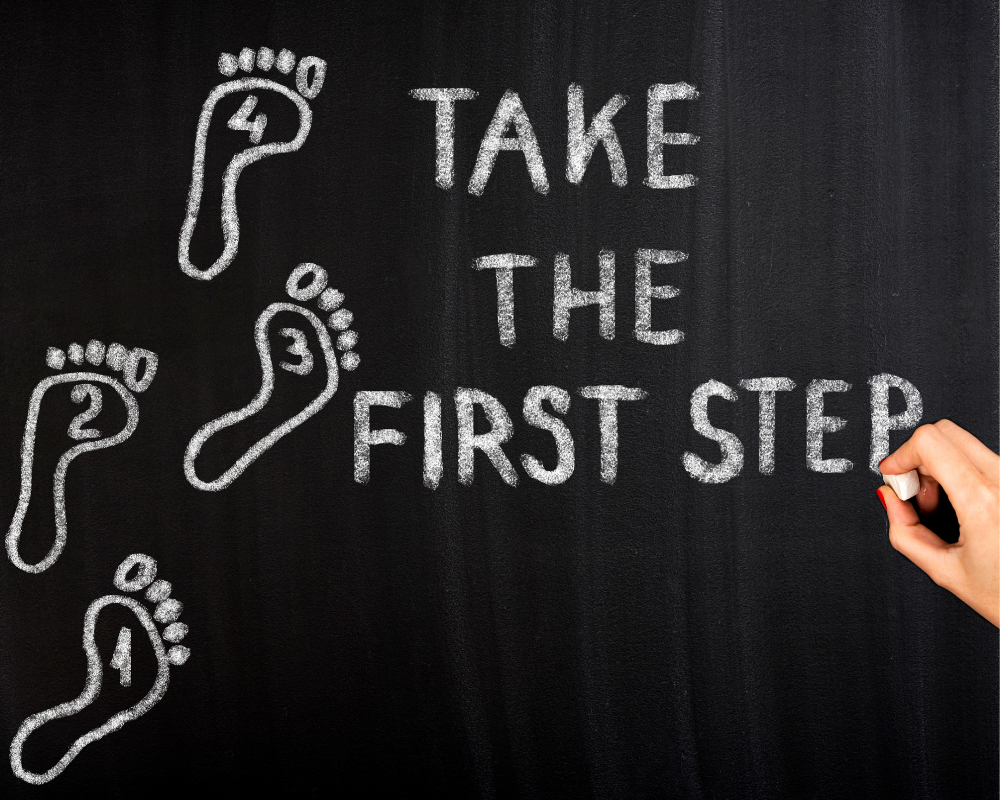 Take the first step written on a chalkboard with footsteps drawn beside it.