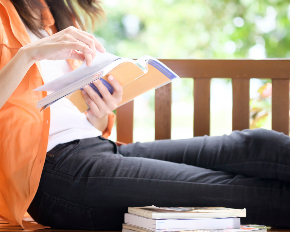 Woman reading, orange shirt, woman reading outside