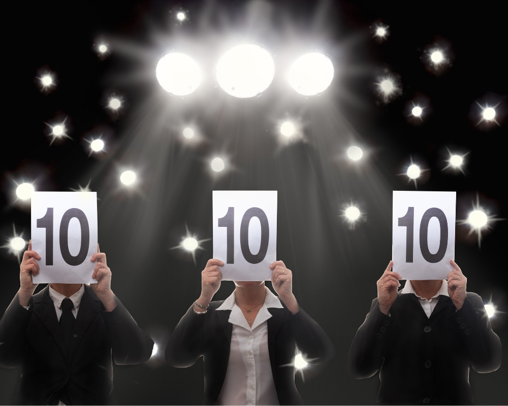 Three people holding up score cards with marks of ten out of ten.