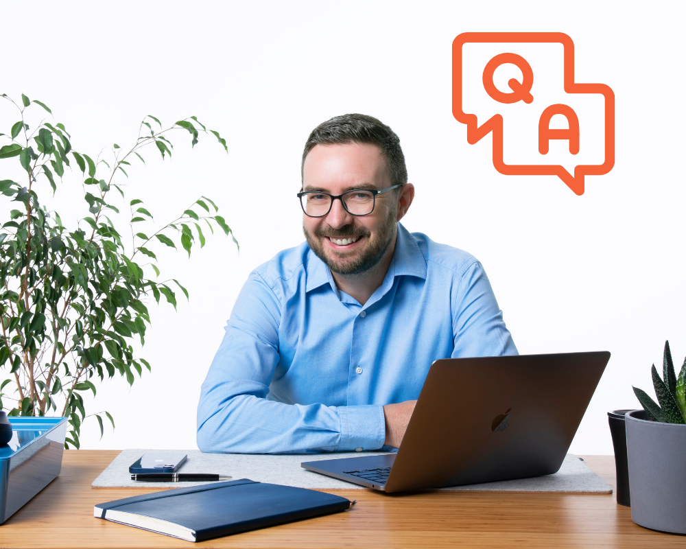 Smiling recruiter at desk with laptop, with “Q&A” icon – featuring a discussion on MedTech recruitment and career insights.