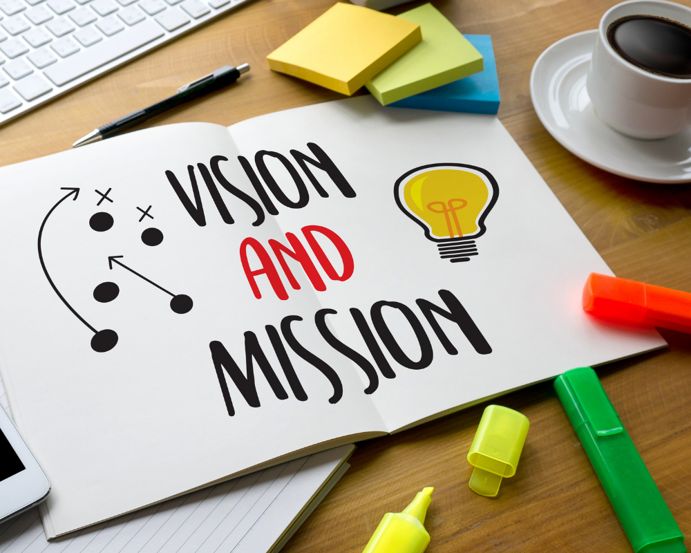 Notebook on a desk with the words vision and mission written in black and red.