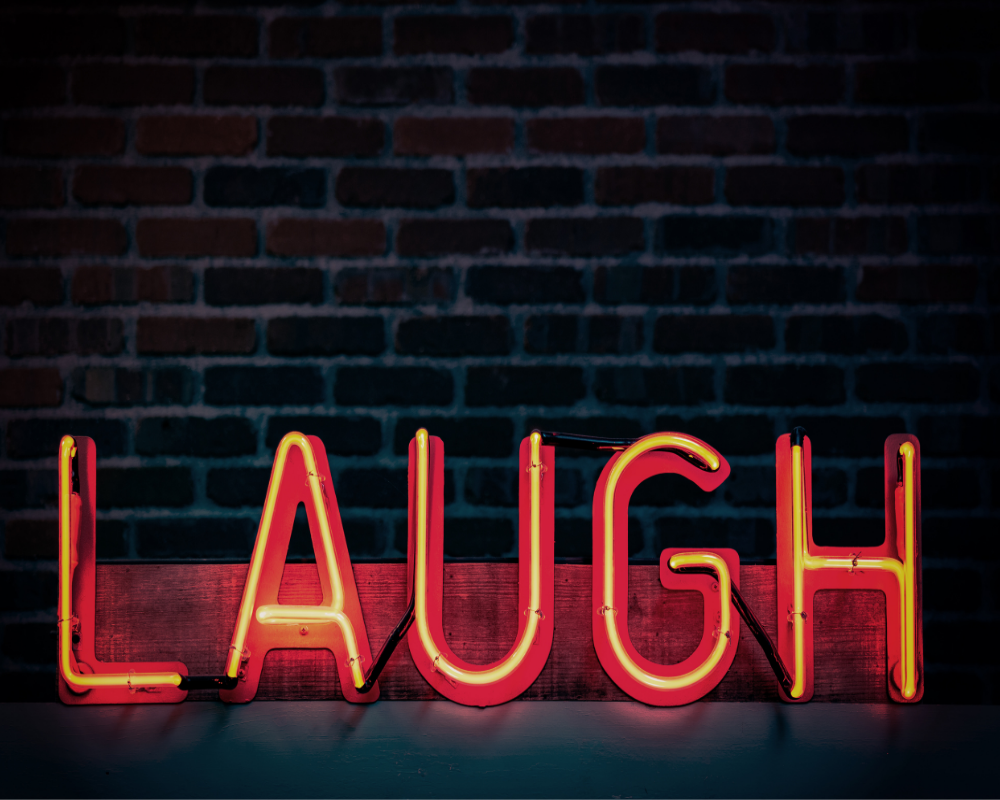 word laugh in a lightbox against a brick wall