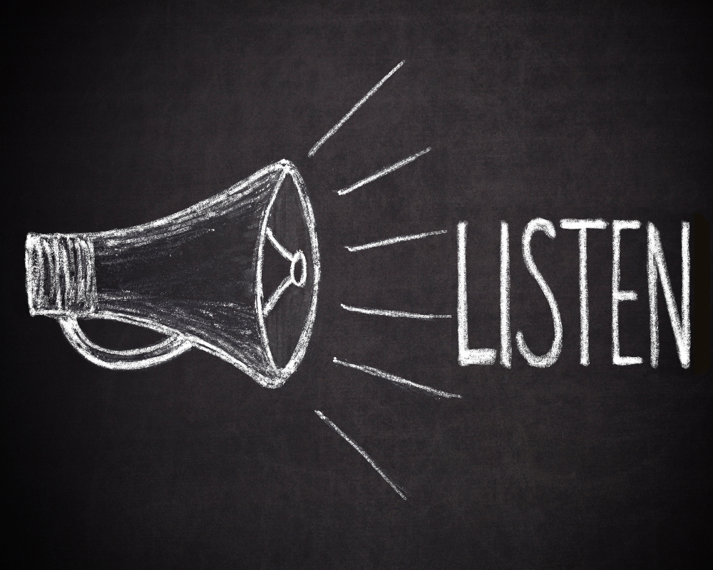 Chalk-drawn megaphone and the word ‘LISTEN’ on a blackboard, emphasizing the importance of active listening in medical sales success.