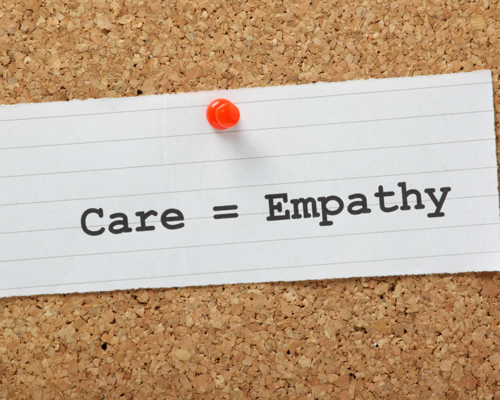 Note on a corkboard with the words care equals empathy