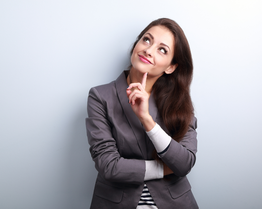 Woman in a grey suit looking up thinking.