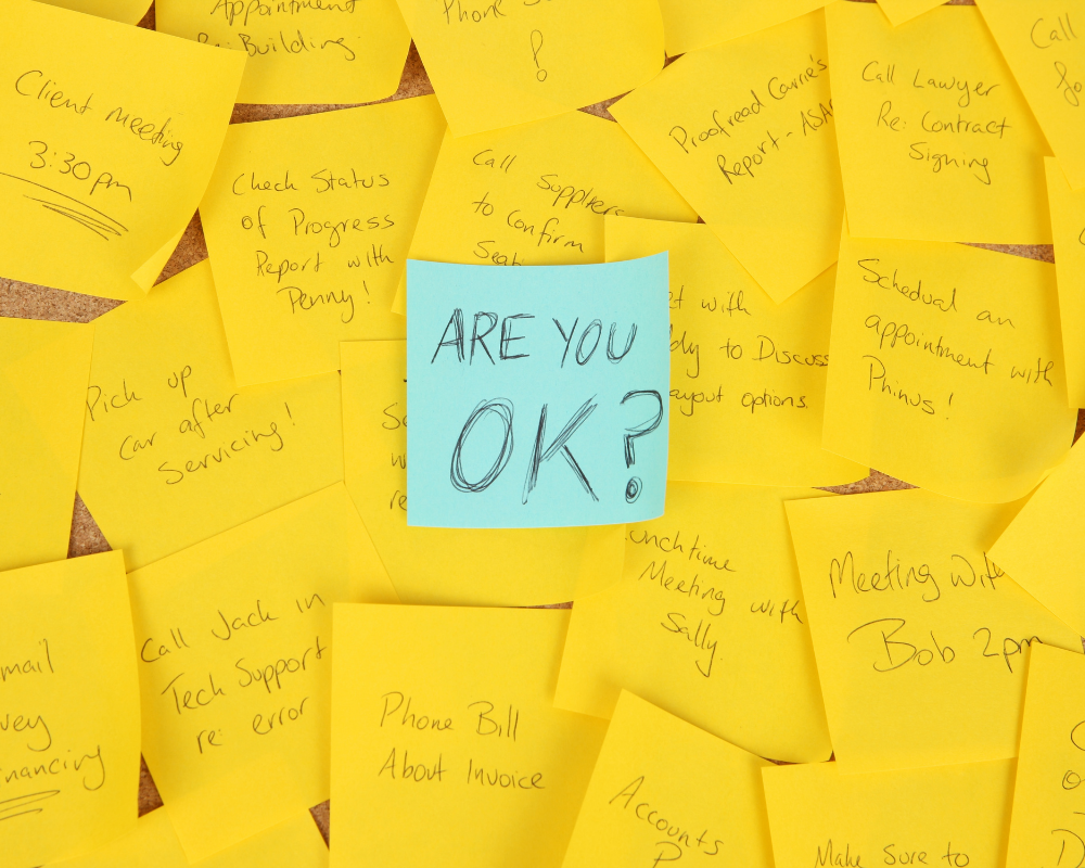 Blue post it with the words are you ok, surrounded by yellow post its.
