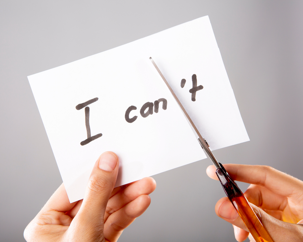 Hand cutting a piece of paper to change “I can’t” into “I can” – symbolising mindset shifts and career growth.