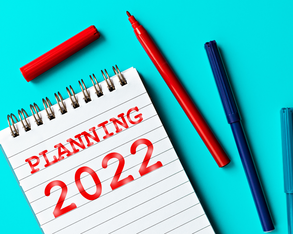 note pad against a blue background with planning 2022 written in red.