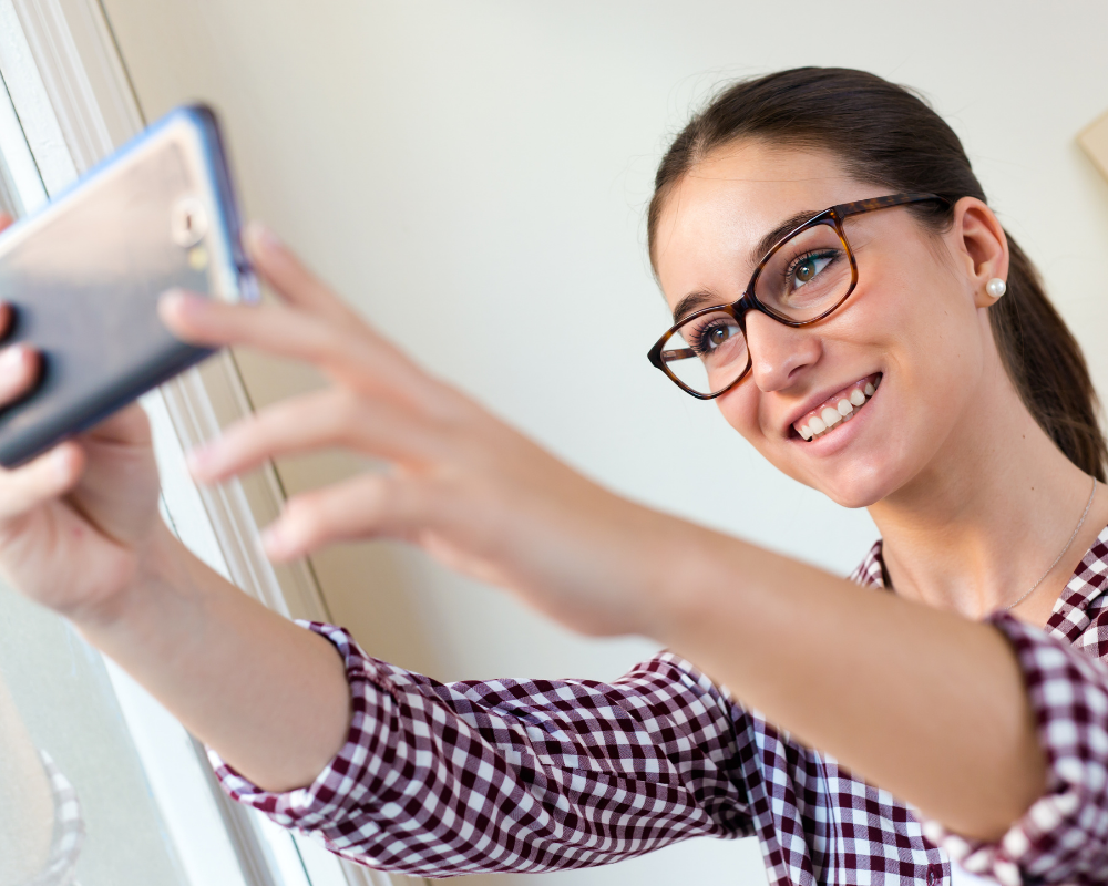 Woman taking a selfie on her phone, representing the importance of a professional LinkedIn profile picture.