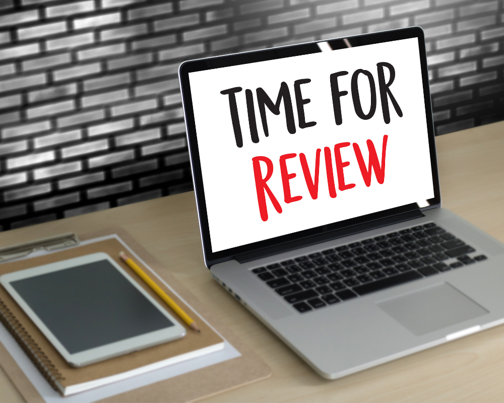 Laptop on a desk with the words time for review written in black and red.