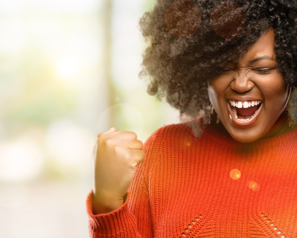 Woman in orange jumper celebrating.