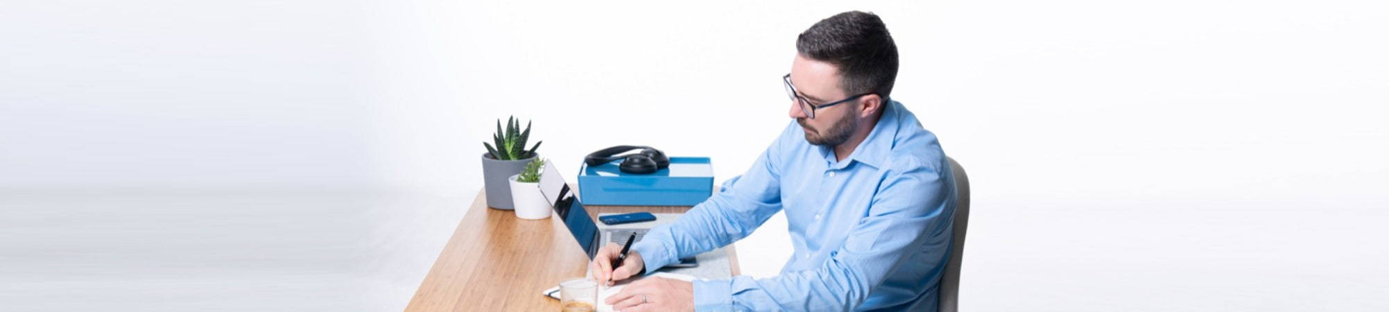 Man at desk writing a blog in a notebook